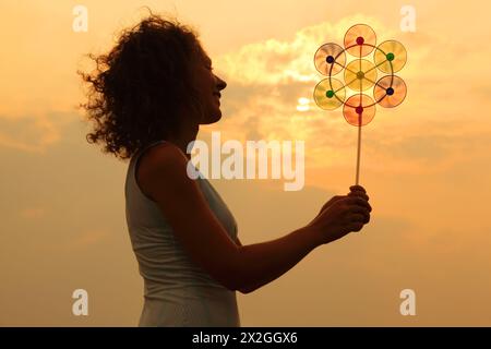 Schöne junge Frau, die ein Spielzeug hält und bei Sonnenuntergang lächelt Stockfoto