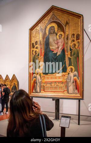 Florenz, Italien - 4. April 2024: Weibliche Besucherin hört Audioguide, während sie Giottos Werk Madonna thront mit Kind unter Engeln und Sa beobachtet Stockfoto