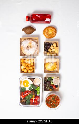 Eine Vielzahl köstlicher Speisen in Behältern auf weißem Hintergrund. Das Essen beinhaltet ein Getränk, Brot, Salat, Suppe und andere Dinge. Stockfoto