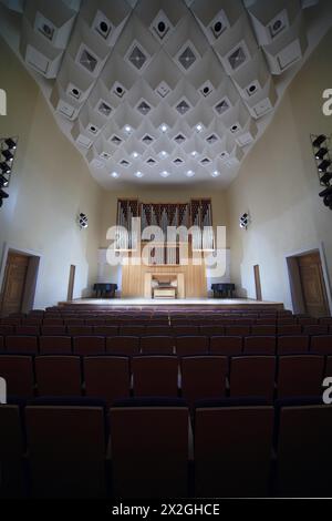 Massive hölzerne Pfeifenorgel im leeren Konzertsaal; hell beleuchtete Bühne Stockfoto