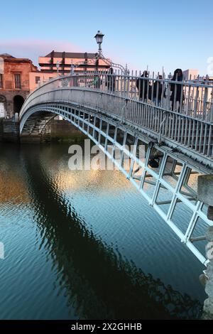 Leute, die auf der Ha'Penny Bridge, Liffey River in Dublin, Irland, fahren Stockfoto