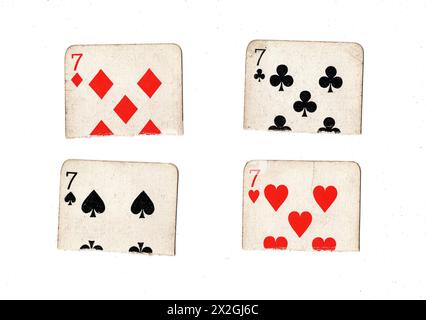 Zerrissene Hälften von Vintage-Spielkarten, die sieben in allen vier Anzügen auf weißem Hintergrund zeigen. Stockfoto