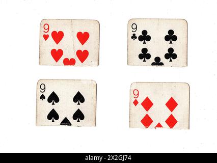 Zerrissene Hälften von Vintage-Spielkarten, die neun in allen vier Anzügen auf weißem Hintergrund zeigen. Stockfoto