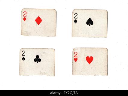 Zerrissene Hälften von Vintage-Spielkarten, die zwei in allen vier Anzügen auf weißem Hintergrund zeigen. Stockfoto