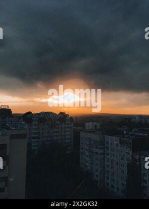 Eine atemberaubende Skyline der Stadt bei Sonnenuntergang mit einem dramatischen Himmel voller dunkler Wolken und dem warmen Schein der untergehenden Sonne. Stockfoto