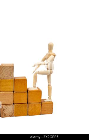 Hölzerne Schaufensterpuppe, die auf Holzblöcken klettert, isoliert auf weißem Hintergrund Stockfoto