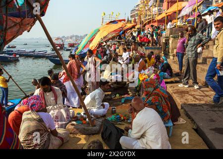Hindupriester oder Pujaris unter großen Regenschirmen führen spirituelle Hindurituale für Pilger im Dashashwamedh Ghat in Varanasi, Indien, durch Stockfoto
