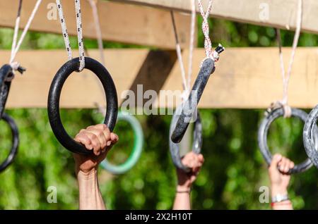 Selektiver Fokus, Athleten Hände an einem hängenden Hindernis mit Metallringen bei einem Hindernisrennen, OCR Stockfoto