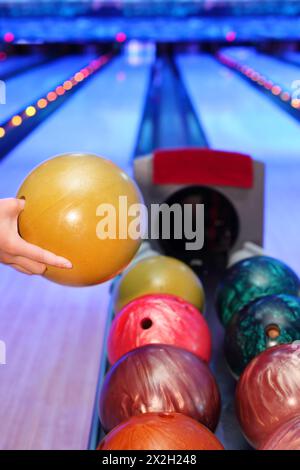 Hand of man, die gelbe Kugel zum Werfen im Bowlingclub nimmt Stockfoto