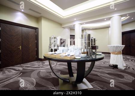 Großer Wasserkocher mit Geschirr auf Stehparty im geräumigen Saal bei der Konferenz Stockfoto