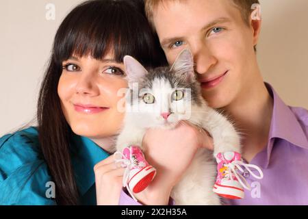 Glückliche junge Ehemann und Ehefrau halten die Katze in roten Stiefeln; konzentrieren Sie sich auf die Katze Stockfoto
