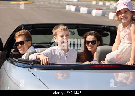 Glücklicher Vater, Mutter und zwei Kinder sitzen in einem Cabrio und blicken zurück; konzentrieren Sie sich auf die Kinder Stockfoto