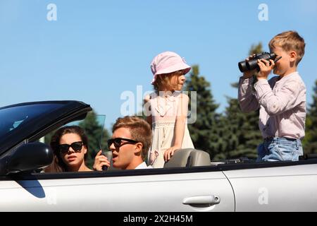 Glücklicher Vater, Mutter und zwei Kinder fahren im Cabriolet und spielen; konzentrieren Sie sich auf den Mann Stockfoto