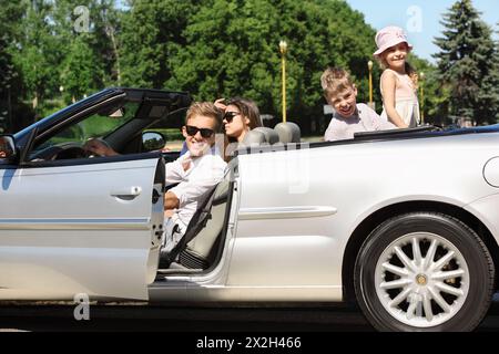 Glücklicher Vater, Mutter und zwei Kinder sitzen in einem schönen Cabrio Stockfoto