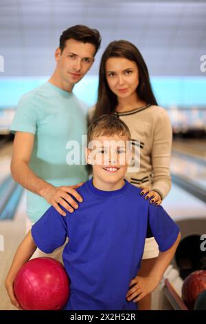 Junger Vater und Mutter mit Sohn im Bowlingclub; Fokus auf Jungen; geringe Feldetiefe Stockfoto