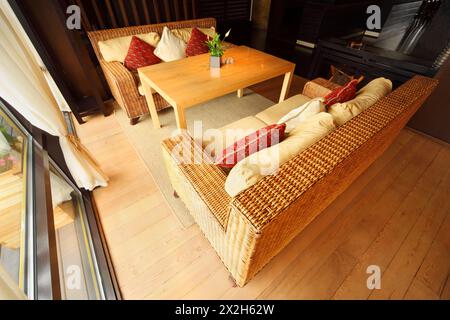 Zwei Korbsofas mit Kissen und Tisch in einem leeren, komfortablen Restaurant am Tag Stockfoto
