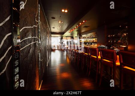 Bartheke mit roten hohen Stühlen in leerem, komfortablem Restaurant Stockfoto