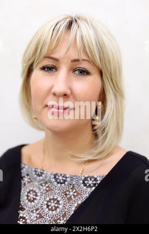 Porträt lächelnd einer blonden Frau in schwarzem Kleid mit weißer Spitze Stockfoto