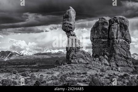 Der legendäre Balanced Rock vor den La Sal Mountains und einem stimmungsvollen Himmel im Arches National Park in der Nähe von Moab, Utah. Stockfoto