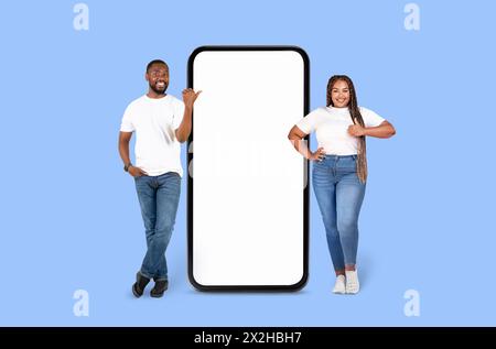 Lächelnder Mann, der auf Smartphone-Mockup mit Frau zeigt Stockfoto