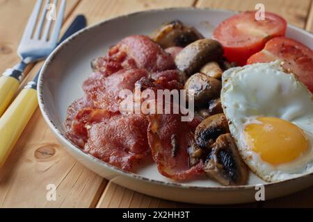 Gebratenes Frühstück mit Speck, Eiern, Pilzen und Tomaten. Stockfoto