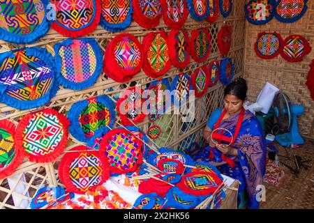 22. April 2024, Narayanganj, Dhaka, Bangladesch: Arbeiter sticken Handfans mit bunten geometrischen Formen in Narayanganj, Bangladesch. Sie verwenden Bambus und buntes Garn, um aufwändig gestaltete Fans zu kreieren. In heißen Sommern gibt es eine kühle Brise, die hilft, wenn es draußen wirklich heiß ist, wenn es im Falle eines Lastabfalls hilft. Jeder Arbeiter macht bis zu 10 Fans pro Tag, wobei jeder Fan für rund 1,20 USD auf Dorfmessen verkauft wird. Dieser Beruf ist in der Gegend zu einem traditionellen Beruf geworden, und sie machen seit Hunderten von Jahren Handfans. Trotz ihrer ausgezeichneten Qualität sind die Handfans sol Stockfoto