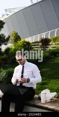 Männlicher Freelancer, der aus der Ferne online mit Kopfhörern und Laptop-Videoanruf Konferenz- oder Entfernungskonferenz arbeitet männlich im Stadtpark auf einer Bank ein moderner Stockfoto
