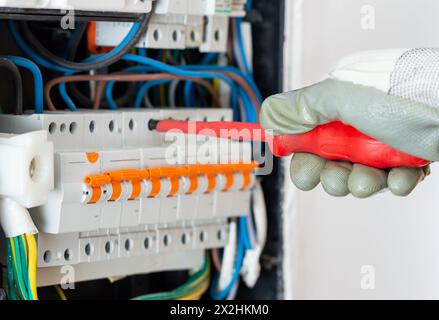 Eine Kurzzusammenfassung des Elektrikers arbeitet mit den elektrischen Kabeln des Sicherungs-Schaltkastens. Elektrische Anlagen und Automatik. Stockfoto