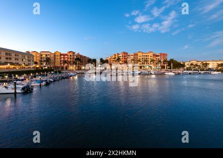 Naples, Florida, USA - die Dämmerung lässt sich auf Neapel nieder mit Gebäuden am Wasser und Booten unter klarem Himmel. Stockfoto