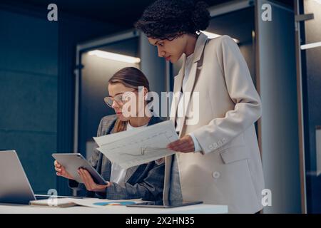 Zwei weibliche Kollegen diskutieren das Projekt, bevor sie der Teamleiterin im Büro eine Präsentation zeigen Stockfoto