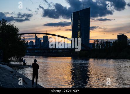 22. April 2024, Hessen, Frankfurt/Main: Ein Mann beobachtet den Sonnenuntergang am Main in Frankfurt. Es wird erwartet, dass das Wetter in den kommenden Tagen kühl und regnerisch bleibt. Foto: Boris Roessler/dpa Stockfoto