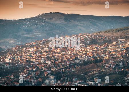 Panorama von Sarajevo, während die Sonne hinter den sanften Hügeln untergeht und einen farbenfrohen Farbton über das Stadtbild wirft. Stockfoto