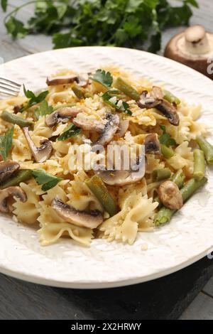 Vegetarische Pasta mit Pilzen, Petersilie, Bohnen und Käse auf grauem Holztisch, Nahaufnahme Stockfoto