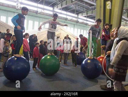 Kinder von Flüchtlingen spielten zwischen Zelten in einem Notunterstand für Flüchtlinge am 9. Dezember 2015 im ehemaligen Hangar des Flughafens Tempelhof, Berlin Stockfoto