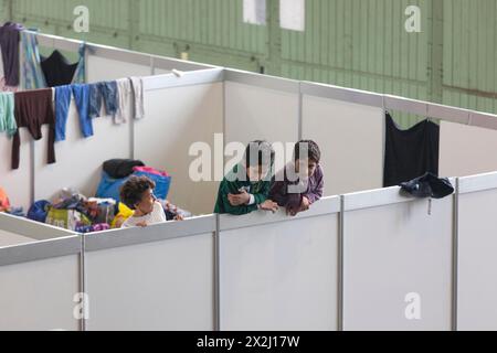 Flüchtlingskinder schauen am 9. Dezember 2015 im ehemaligen Hangar von Tempelhof über die Wand eines provisorischen Zimmers in einem Notunterstand für Flüchtlinge Stockfoto