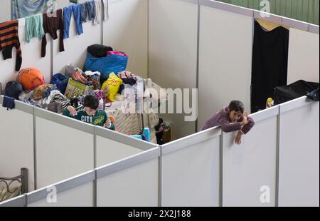 Flüchtlingskinder schauen am 9. Dezember 2015 im ehemaligen Hangar von Tempelhof über die Wand eines provisorischen Zimmers in einem Notunterstand für Flüchtlinge Stockfoto