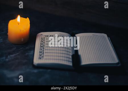 Darck Foto von Notizblock mit einer Liste von Fällen bei Kerzenlicht. Hochwertige Fotos Stockfoto
