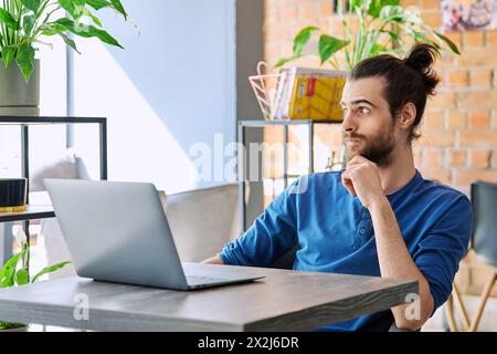 Junger ernsthafter Mann, der arbeitet, mit Laptop studiert und im Coworking-Café sitzt Stockfoto