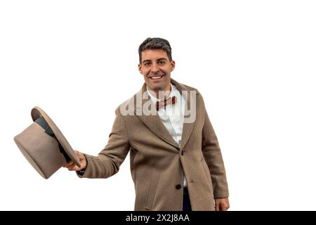 Ein alter Gentleman aus dem frühen 20. Jahrhundert, der einen Bowler-Hut und einen Trenchcoat trägt, beugt sich anmutig in einer Geste der Respec zur Kamera Stockfoto