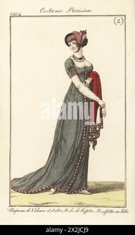 Frau in rosa Satin und schwarzem Samtmütze unter dem Kinn gebunden, tief geschnittenes Taffeta-Gewand mit rosa Satin-Bouffetten, die einen scharlachroten Schal halten. Chapeau de Velours et satin. Robe de Taffetas. Bouffettes en Satin. Pl. 519 in der Pariser Ausgabe. Handkolorierter Kupferstich aus Pierre de la Messengere’s Journal des Dames et des Modes, Francfort sur le mein (Frankfurt) 1804. Nach Illustrationen von Carle Vernet, Jean-Francois Bosio, Dominique Bosio und Philibert Louis Debucourt. Stockfoto