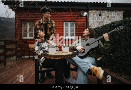 Freunde genießen eine gemütliche Zusammenkunft mit Musik auf einer Veranda. Stockfoto