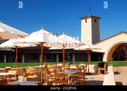 Café-Tische mit Sonnenschirmen stehen im hinteren Bereich der Robert Mondavi Winery in Napa, Kalifornien Stockfoto