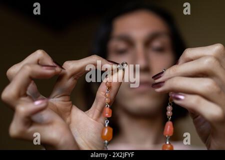 Der junge Transgender-Mann (22) ist in seinem Zimmer und zieht seine Accessoires an. Transgender-Konzept Stockfoto