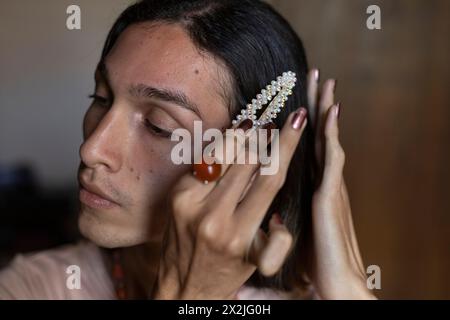 Der junge Transgender-Mann (22) ist in seinem Zimmer und zieht seine Accessoires an. Transgender-Konzept Stockfoto