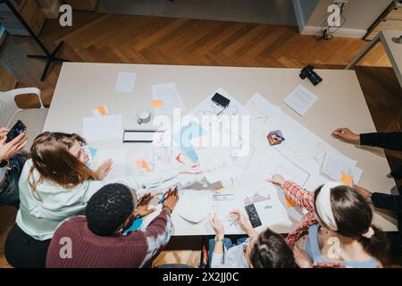 Draufsicht eines Geschäftsteams, das sich während eines dynamischen und kreativen Geschäftstreffens mit Dokumenten und Ideen zusammensetzt. Stockfoto