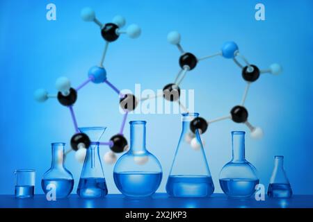 Laborglas und Molekülmodell auf blauem Hintergrund Stockfoto