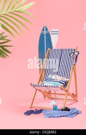 Liegestuhl, Strandaccessoires und ein Glas Cocktail auf rosa Hintergrund Stockfoto