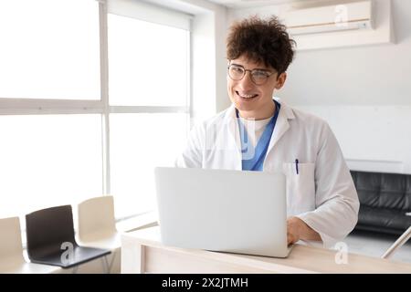 Männlicher Arzt mit Laptop an der Rezeption in der Klinik Stockfoto