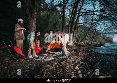 Freunde, die während eines Abenteuers im Freien einen Campingplatz in der Nähe des Flusses einrichten Stockfoto