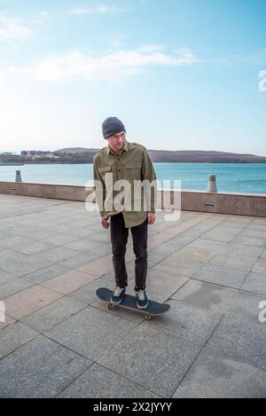 Junger Mann, der auf einem Skateboard fährt und Tricks und Sprünge macht Stockfoto